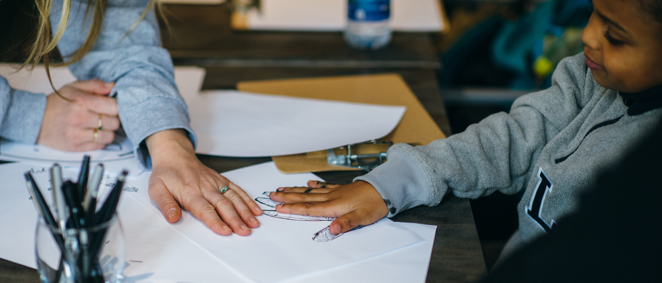 Photograph of an art instructor working with a child on their drawing